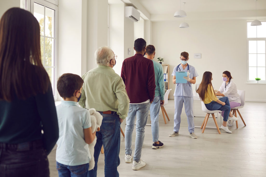 Diverse people lining up waiting for their turn to get shots at the hospital